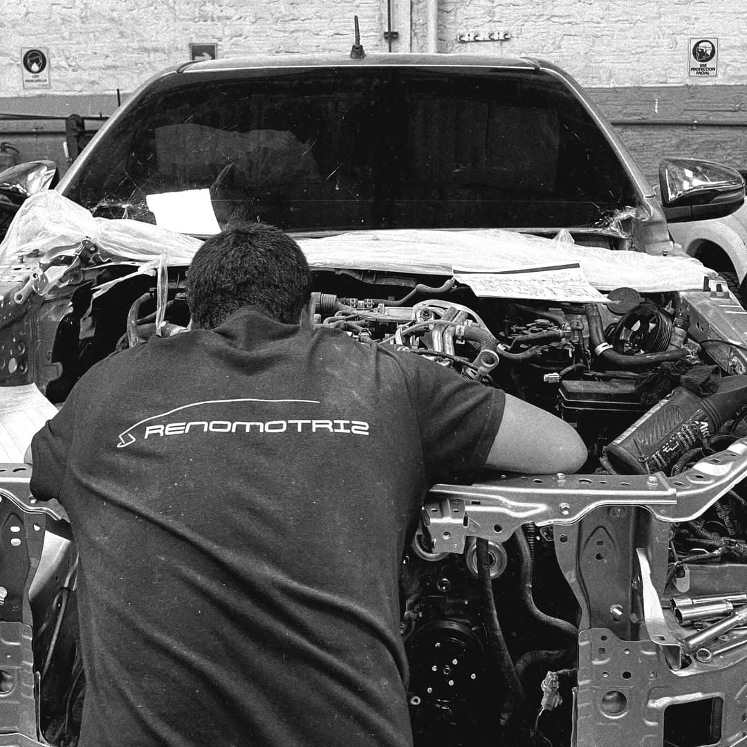 Técnico de Reno Motriz trabajando en el frente desarmado de una camioneta